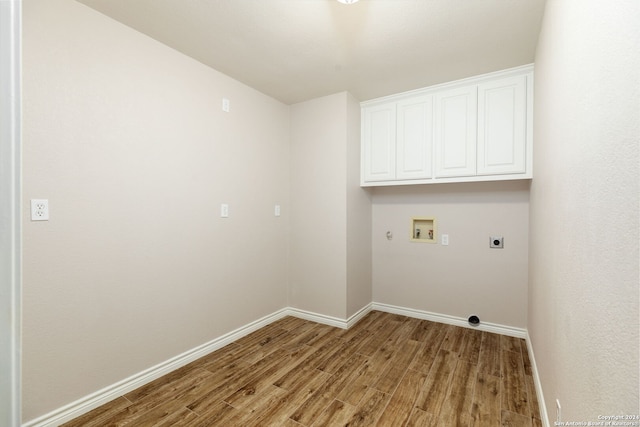 washroom with washer hookup, electric dryer hookup, light hardwood / wood-style floors, and cabinets