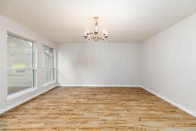 unfurnished room with light hardwood / wood-style floors and a notable chandelier