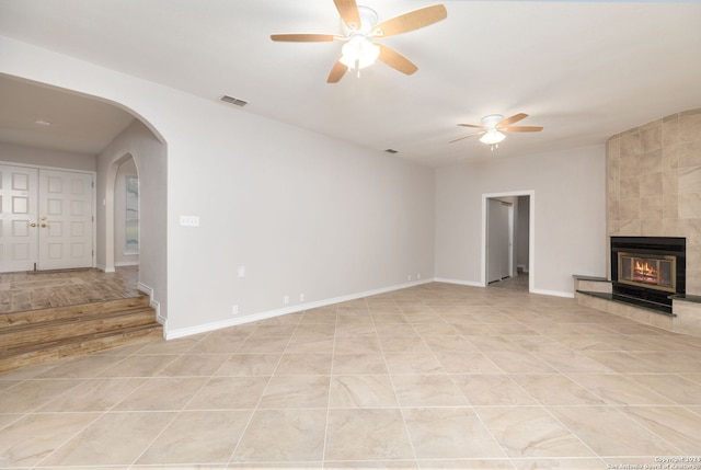 unfurnished living room with light tile patterned floors, ceiling fan, and a tiled fireplace