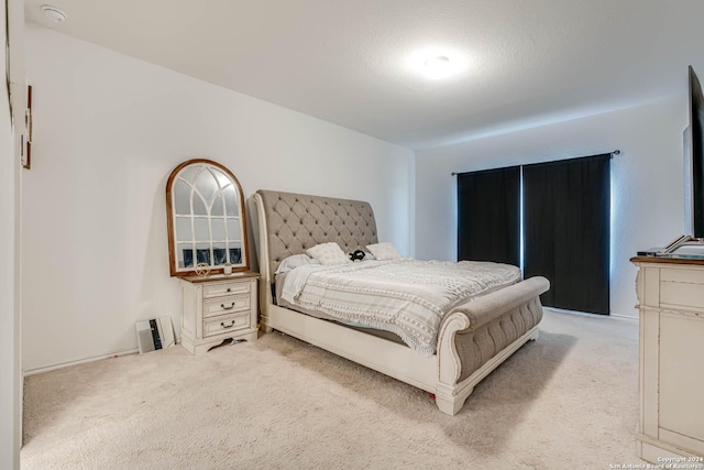 bedroom featuring light colored carpet and a textured ceiling