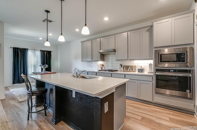 kitchen featuring hanging light fixtures, a kitchen island with sink, sink, and stainless steel appliances