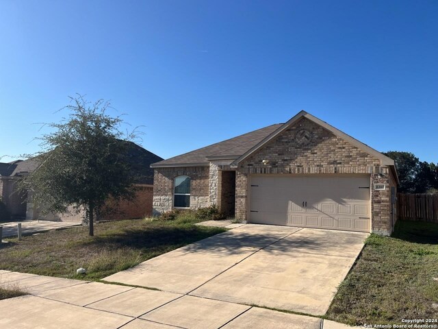 ranch-style house featuring a garage and a front lawn