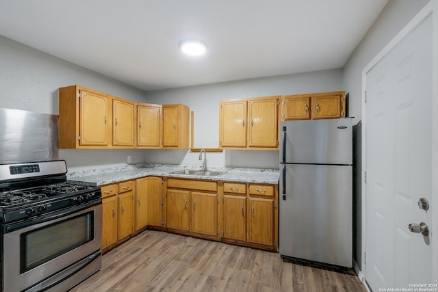 kitchen featuring light stone counters, sink, light hardwood / wood-style flooring, and appliances with stainless steel finishes