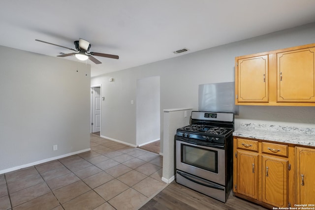 kitchen with light tile patterned floors, stainless steel gas stove, and ceiling fan