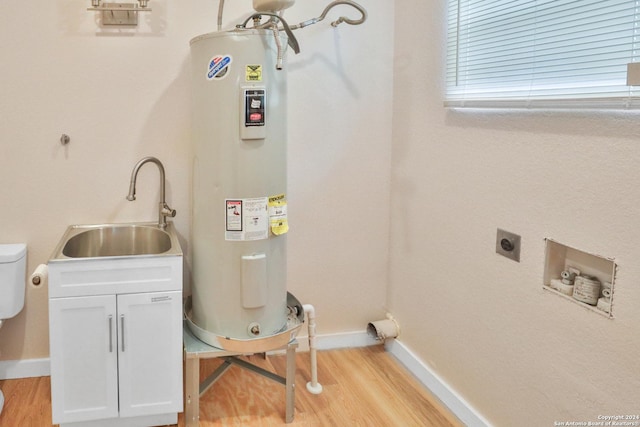 washroom with cabinets, light wood-type flooring, electric dryer hookup, sink, and water heater