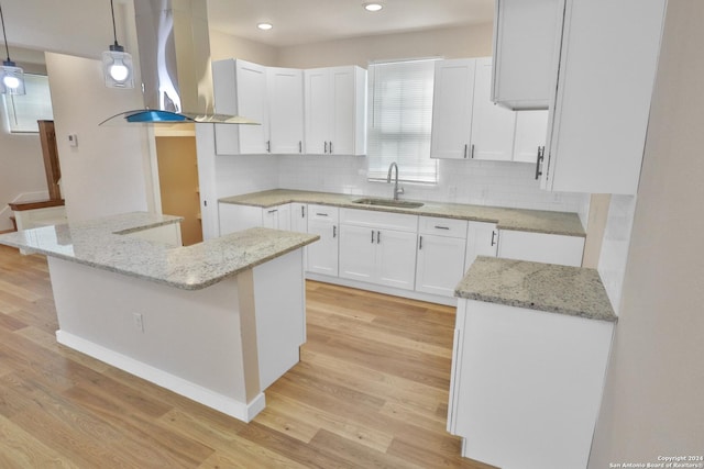 kitchen featuring sink, decorative light fixtures, island range hood, white cabinets, and light wood-type flooring