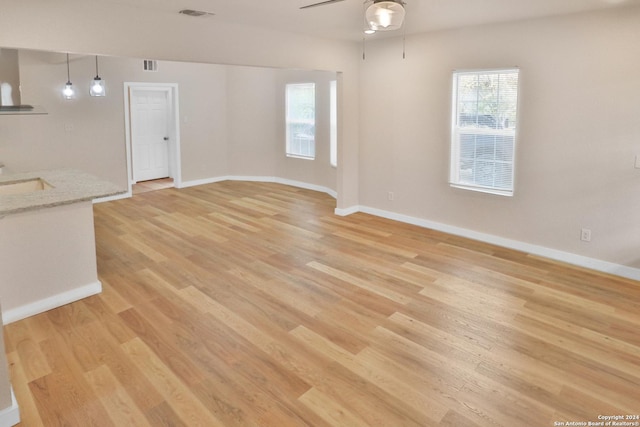 unfurnished living room with ceiling fan, a healthy amount of sunlight, and light wood-type flooring