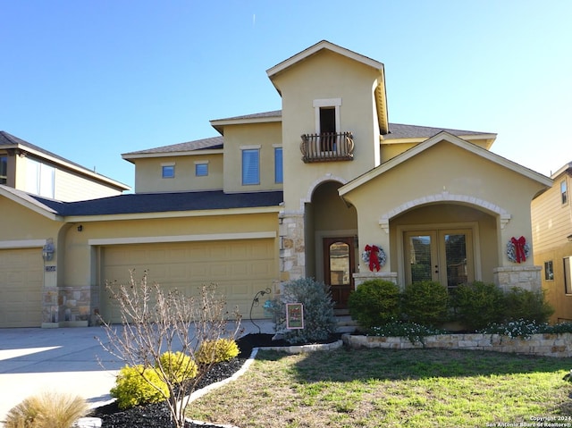 view of front of house featuring french doors, a balcony, a garage, and a front lawn