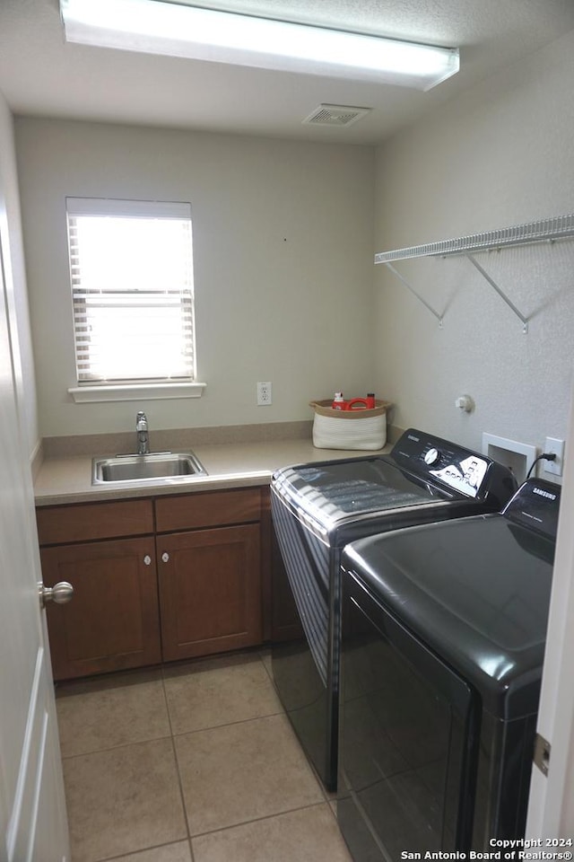 laundry area featuring washer and dryer, light tile patterned flooring, cabinets, and sink