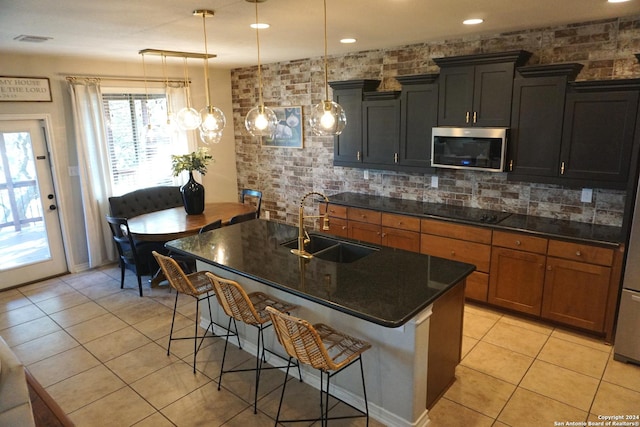 kitchen featuring a breakfast bar, a kitchen island with sink, sink, pendant lighting, and light tile patterned floors