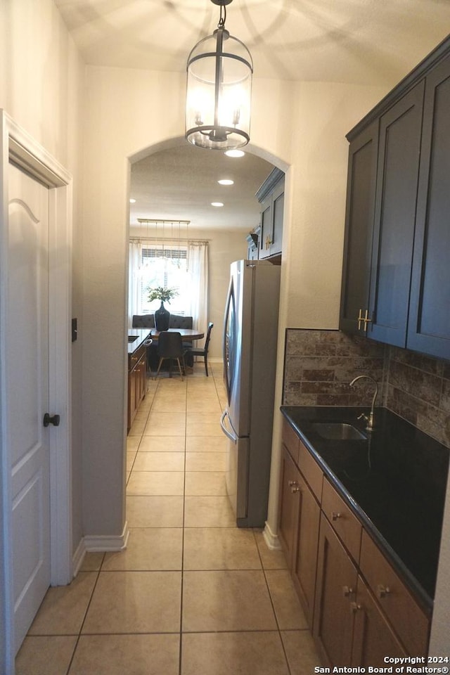 kitchen with backsplash, sink, stainless steel fridge, light tile patterned flooring, and a chandelier