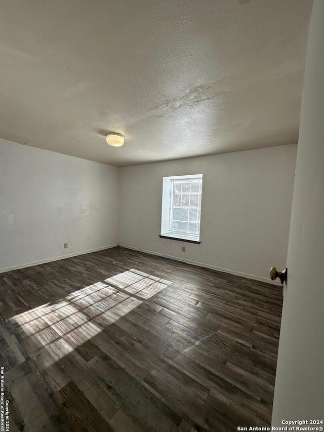 unfurnished room with dark hardwood / wood-style flooring and a textured ceiling