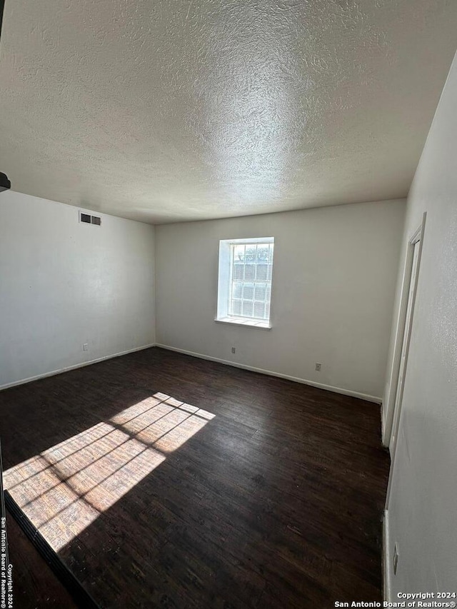 empty room featuring dark hardwood / wood-style flooring and a textured ceiling