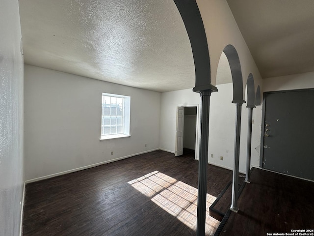 unfurnished living room featuring a textured ceiling and dark hardwood / wood-style floors