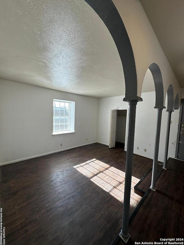 interior space with a textured ceiling and dark hardwood / wood-style floors