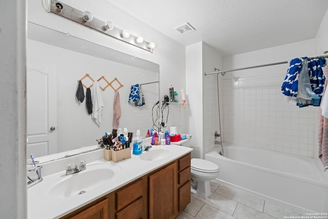 full bathroom featuring vanity, tile patterned floors, tiled shower / bath, toilet, and a textured ceiling