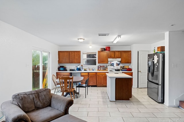 kitchen with electric range, a center island, light tile patterned floors, and stainless steel refrigerator with ice dispenser