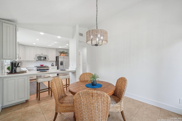 dining area featuring light tile patterned floors, an inviting chandelier, and lofted ceiling