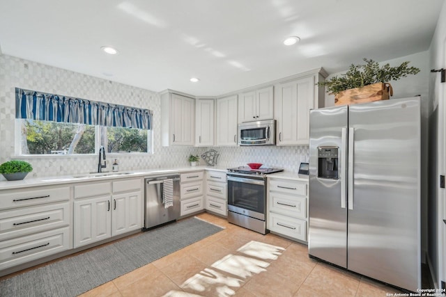 kitchen with sink, tasteful backsplash, light tile patterned flooring, white cabinetry, and stainless steel appliances