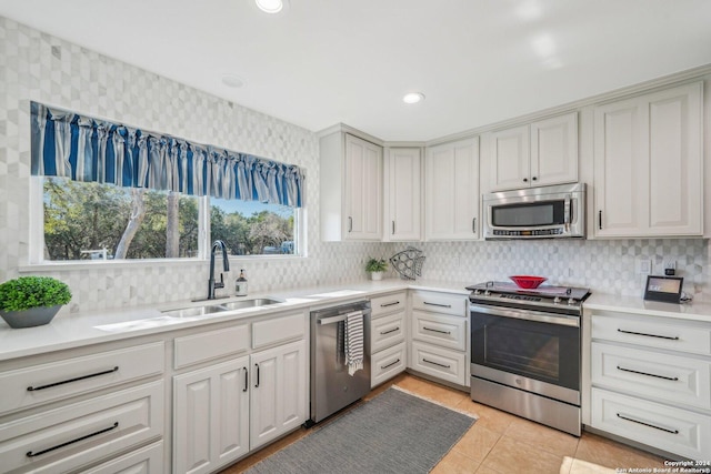 kitchen featuring light tile patterned flooring, appliances with stainless steel finishes, backsplash, and sink