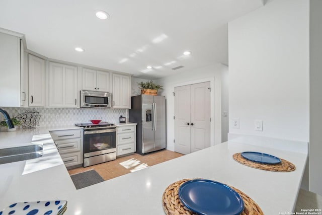 kitchen with light tile patterned floors, sink, appliances with stainless steel finishes, and tasteful backsplash