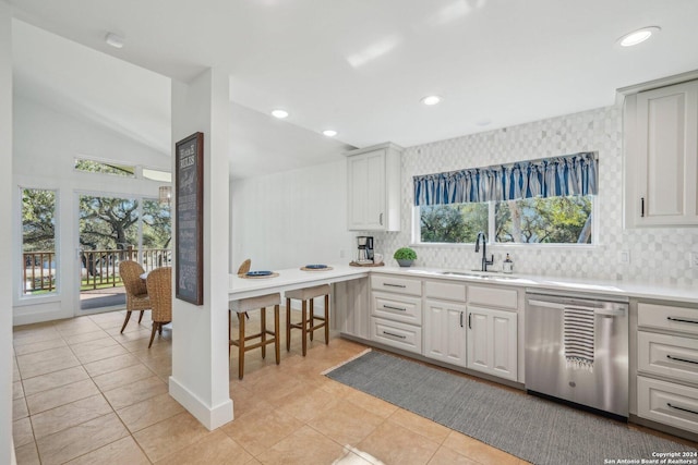 kitchen featuring decorative backsplash, vaulted ceiling, sink, dishwasher, and white cabinetry