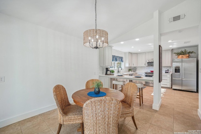 dining space with sink, light tile patterned floors, lofted ceiling, and a notable chandelier