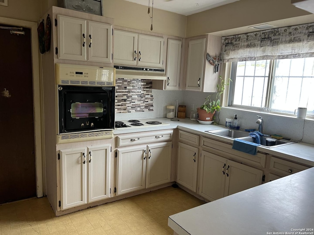 kitchen featuring backsplash, sink, oven, and white stovetop