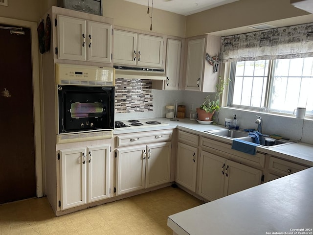 kitchen featuring backsplash, sink, oven, and white stovetop