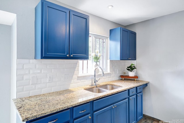 kitchen with blue cabinets, sink, and tasteful backsplash