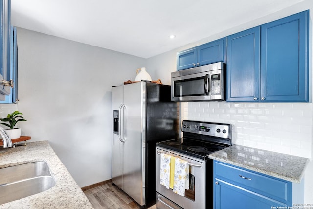 kitchen with sink, light hardwood / wood-style flooring, light stone countertops, blue cabinetry, and appliances with stainless steel finishes