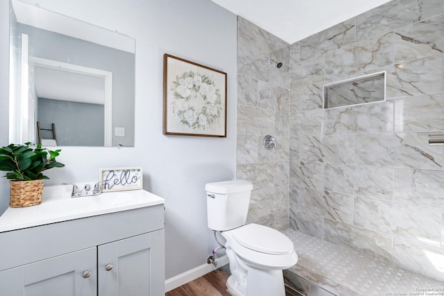 bathroom with tiled shower, hardwood / wood-style floors, vanity, and toilet