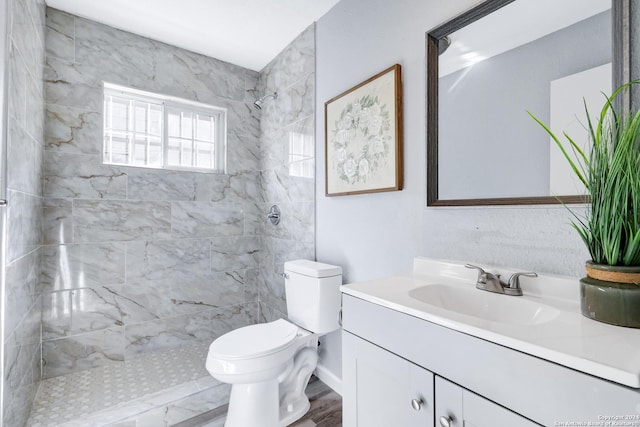 bathroom with tiled shower, vanity, wood-type flooring, and toilet