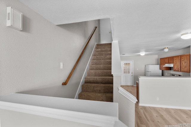 staircase with a textured ceiling and hardwood / wood-style flooring