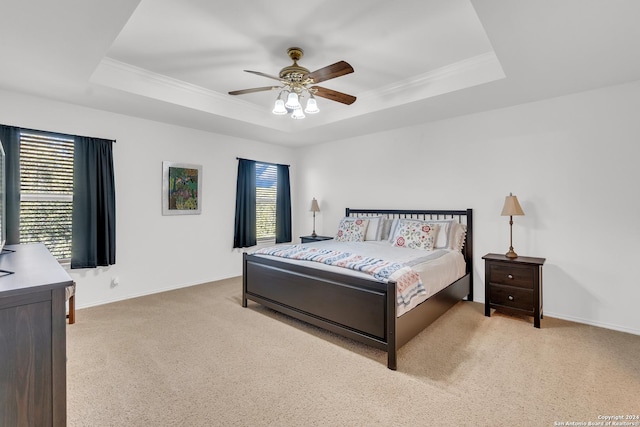 bedroom featuring light colored carpet, a raised ceiling, and ceiling fan