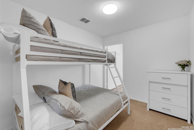 bedroom with light colored carpet and a textured ceiling