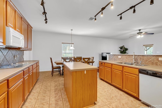 kitchen with a healthy amount of sunlight, a center island, white appliances, and sink