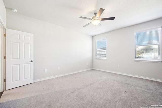 empty room featuring ceiling fan and light colored carpet