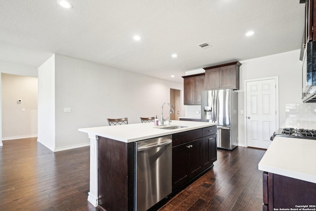 kitchen with dark hardwood / wood-style flooring, a kitchen island with sink, sink, and appliances with stainless steel finishes