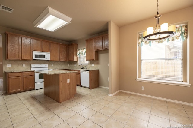 kitchen featuring a center island, white appliances, decorative light fixtures, decorative backsplash, and a notable chandelier