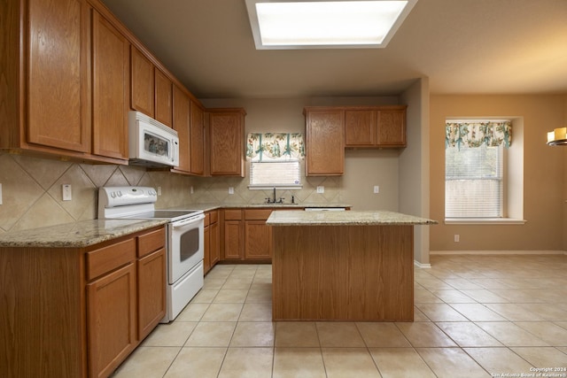 kitchen featuring sink, tasteful backsplash, light stone counters, white appliances, and a kitchen island