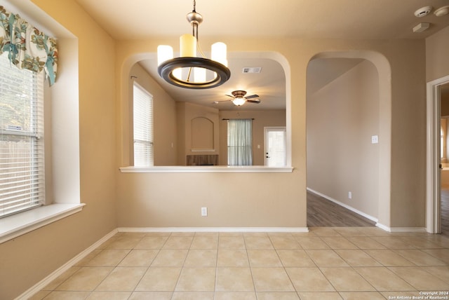 spare room featuring ceiling fan with notable chandelier and light tile patterned flooring