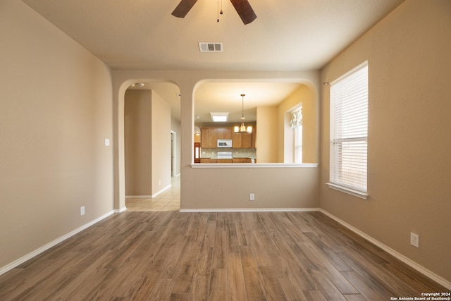 empty room featuring hardwood / wood-style floors and ceiling fan with notable chandelier