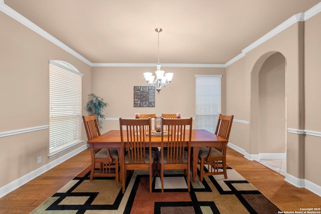 dining room with light hardwood / wood-style flooring, ornamental molding, and an inviting chandelier