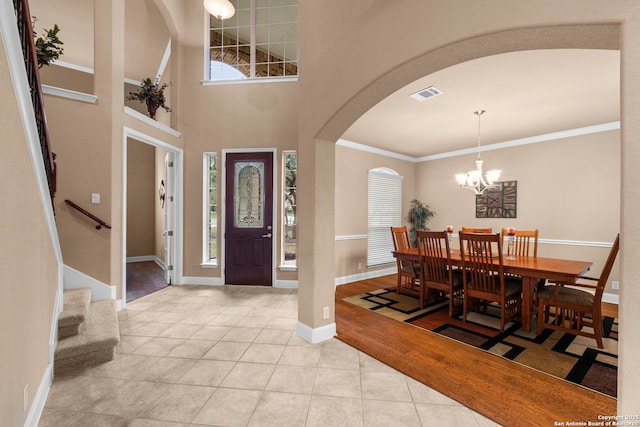 entrance foyer with a chandelier, a high ceiling, ornamental molding, and light tile patterned floors