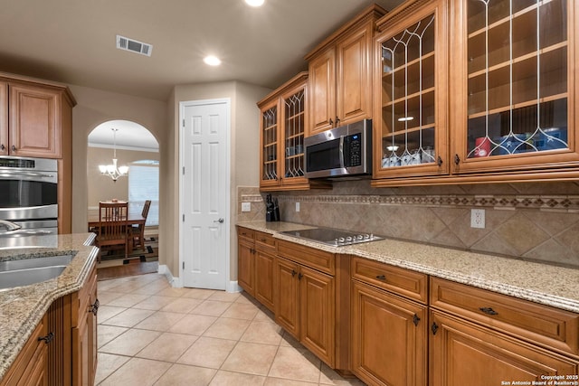 kitchen featuring sink, backsplash, light stone countertops, light tile patterned flooring, and stainless steel appliances