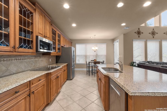 kitchen featuring pendant lighting, appliances with stainless steel finishes, decorative backsplash, sink, and a center island with sink