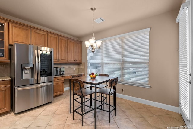 kitchen featuring decorative light fixtures, decorative backsplash, stainless steel fridge, a chandelier, and light tile patterned floors