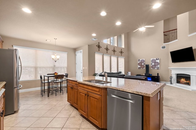 kitchen with light tile patterned floors, sink, pendant lighting, stainless steel appliances, and a center island with sink