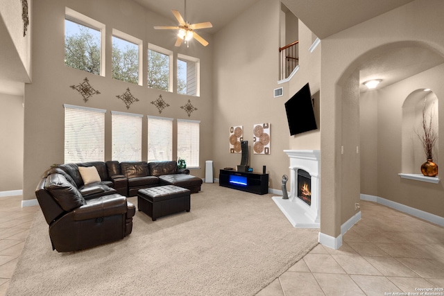 tiled living room with ceiling fan and a high ceiling